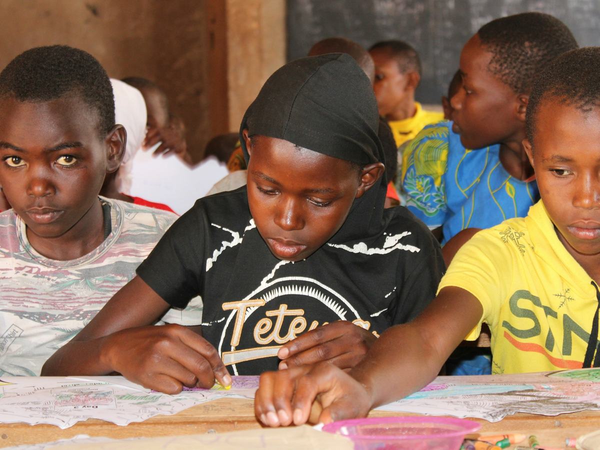 Pupils writing and drawing in a classroom in Mwingi, Kenya