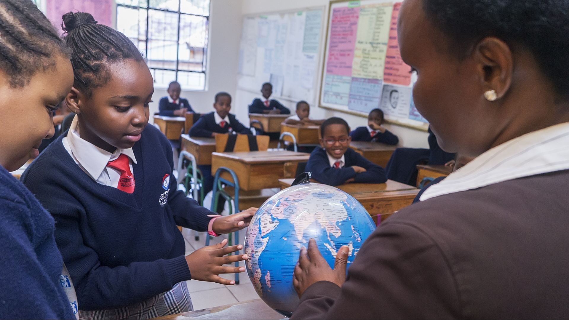 A teacher showing pupils a globe in a Kenyan classroom