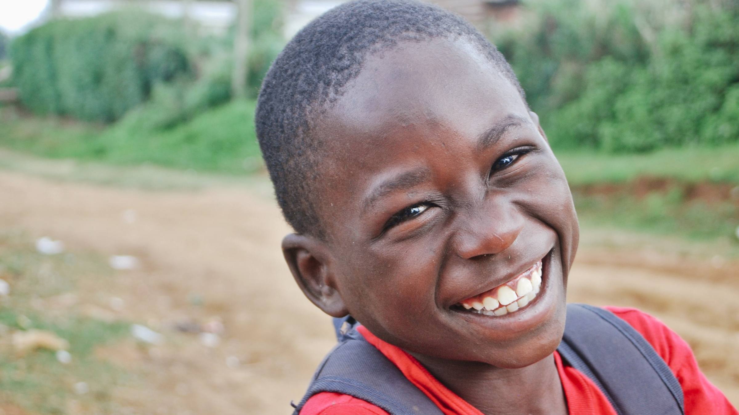A smiling schoolboy with his backpack in Kenya