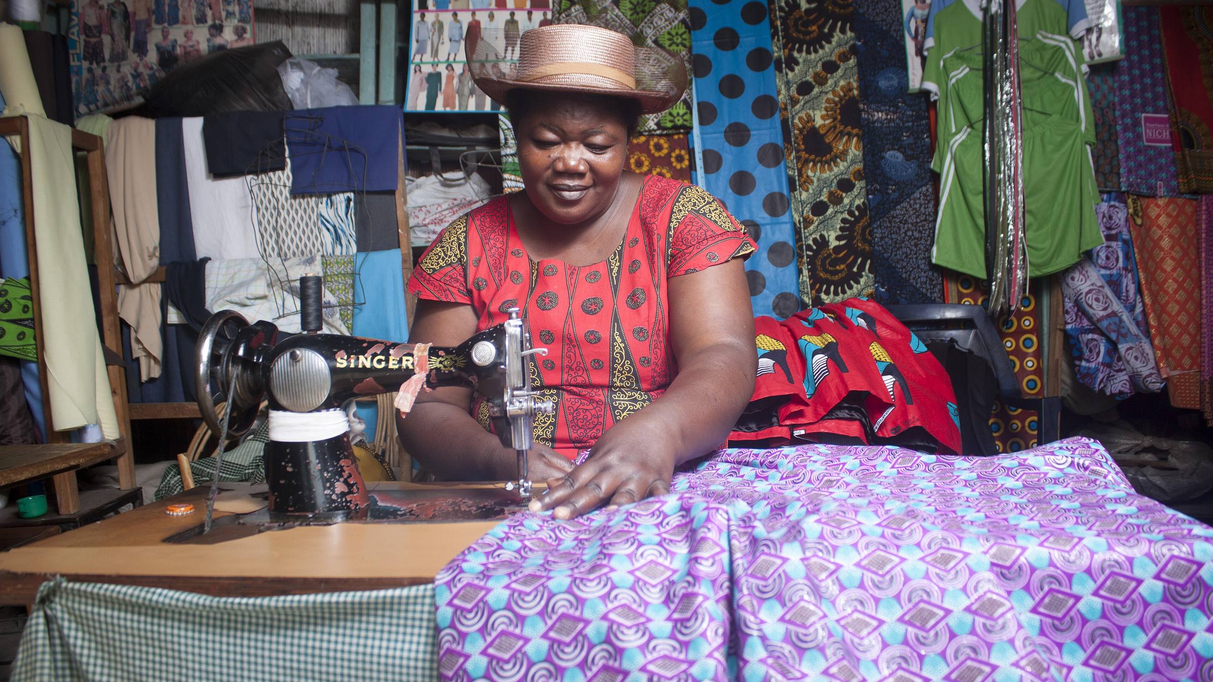 A tailor at her sewing machine among kitenge fabrics in South Nyanza, Kenya
